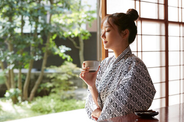 旅館の客室でリラックスをする浴衣姿の若い女性