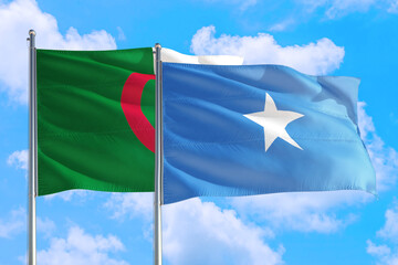 Somalia and Algeria national flag waving in the windy deep blue sky. Diplomacy and international relations concept.