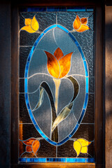 Beautiful stained glass shaping a tulip in several colours, illuminated by sun rays