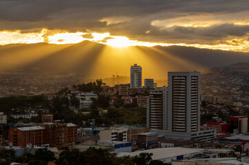 Diagonal sunset light rays coming down over skycrapper in Tegucigalpa, Honduras