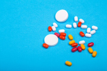Scattered pills and vitamins on a blue background.