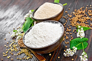 Flour buckwheat green and brown in bowls with flowers on wooden table