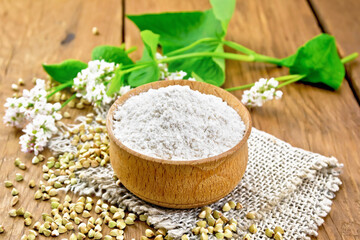 Flour buckwheat green in bowl with flowers on brown board