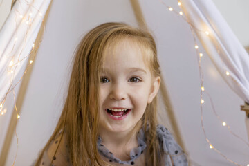 Portrait of a beautiful smiling little girl. Little girl playing in a wigwam © Наталья Мокрецова