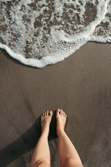 High angle shot of a person standing on the beach near seafoam
