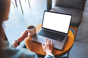 Mockup image of a hand touching on laptop computer touchpad with blank white desktop screen while drinking coffee