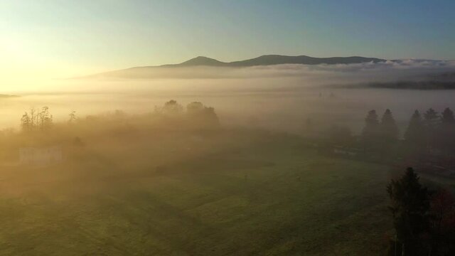 suggestiva ripresa aerea con drone controluce volando sopra una fitta nebbia
