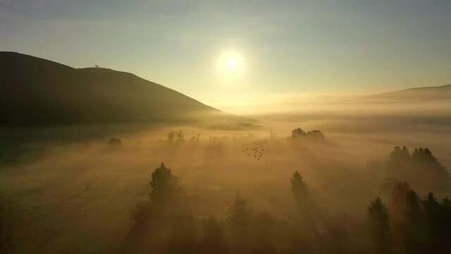 suggestiva ripresa aerea con drone controluce volando sopra una fitta nebbia
