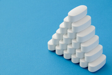pharmacy concept of many white tablets pills on blue background with copy space