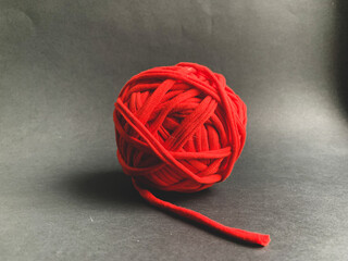 A ball of red knitted yarn on a black background. Knitting, needlework, creating products with your own hands. Hobby
