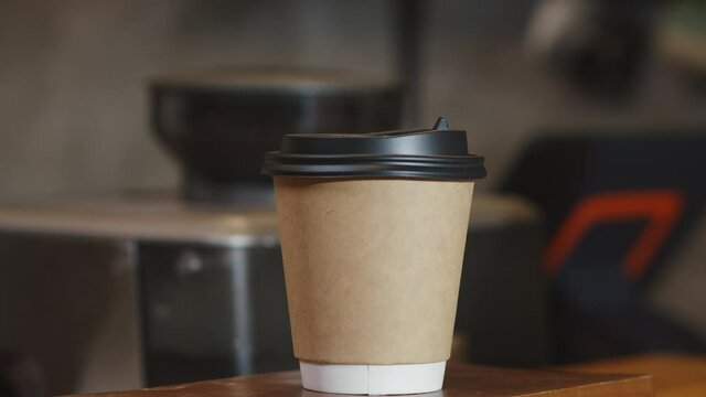 Young Asia female barista serving take away hot coffee paper cup to consumer standing behind bar counter at cafe restaurant. Owner small business, food and drink, service mind concept.