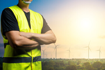 Green energy concept : Maintenance technician wear reflective shirts over black clothes. There is a background in a field of wind turbines for generating electricity.