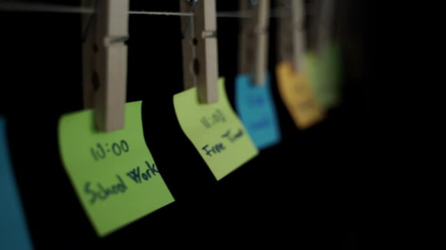 Schedule of student daily activities written on colorful note stickers in black background