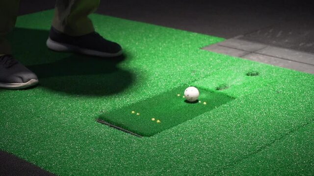 Indoor golf simulator swing with an iron, club hitting ball