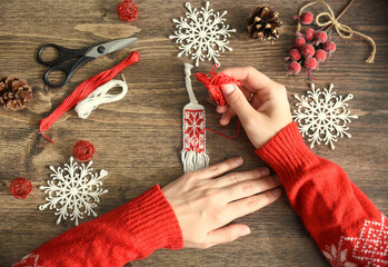Process of weaving friendship bracelet from floss threads.female hands in red sweater braiding...