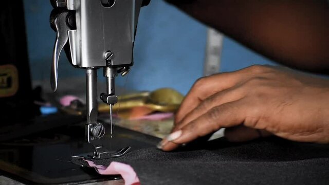 Human hand stiching cloths with sewing machine.