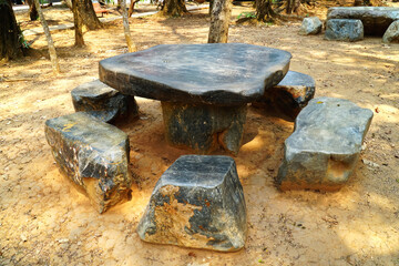 Rock table and chair in the garden background. Large nature stone table and chairs in the park