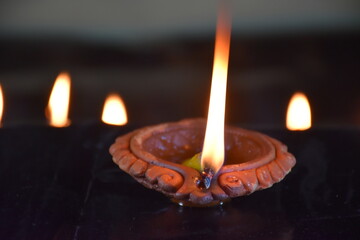 Clay Diya or Oil Lamp lits during the Diwali night. Traditional Diyas lit on gold and black background