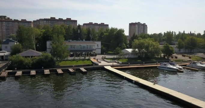 4K high quality calm windless bright summer morning aerial video of Moscow Channel yacht club embankment, green trees, wooden pier and shore with moored anchored boats and yachts near Moscow, Russia