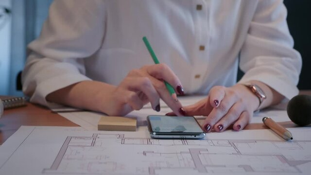 Young pretty engineer, architect or designer woman works with drawings in office