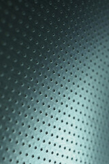 Tinted blue or green metal background. Dark vertical technical wallpaper. Perforated aluminum surface with many holes. Macro
