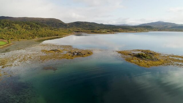 Aerial view of small rocky island, shallow water and alga on the coast of the Senja island, full of autumn colors, in North Norway - tracking, drone shot