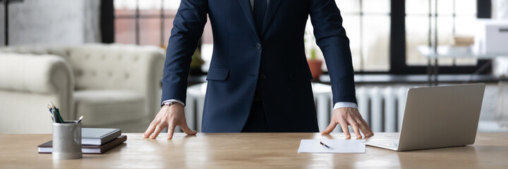 Horizontal cropped photo banner for website header design closeup young unrecognizable businessman in formal wear standing in office with hands put on table, professional services, leadership concept.