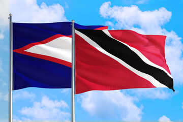 Trinidad And Tobago and American Samoa national flag waving in the windy deep blue sky. Diplomacy...