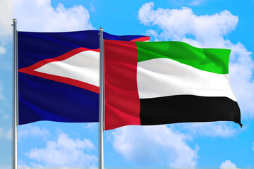 United Arab Emirates and American Samoa national flag waving in the windy deep blue sky. Diplomacy and international relations concept.