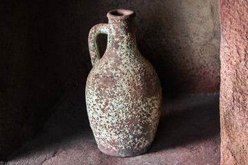 Drinking earthenware jug on stone shelf indoors.