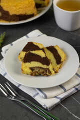 Marmer Cake or marbel Cake on white ceramic, served with a cup of coffee. Black marble background. 