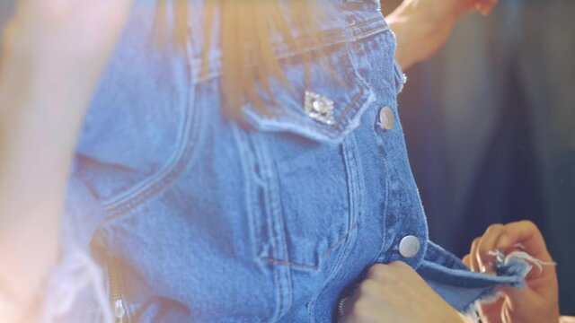 denim office. denim jacket on the model girl.designer buttoning the button of the jacket. designer is working on jean jacket.