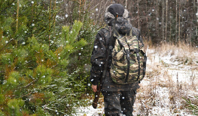 Hunter with a gun and a backpack in the winter forest	
