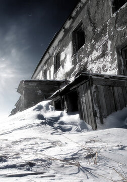 Abandoned building in the Arctic. Large snowdrifts near an abandoned house in the far North of Russia. Cold snowy weather. Harsh polar climate. Gloomy apocalyptic landscape. Empty streets, nobody.