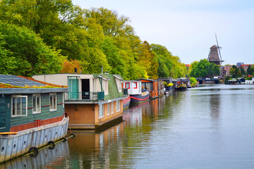 Obraz premium Amstel river with houseboats in Amsterdam city, The Netherlands. Windmill in a background.