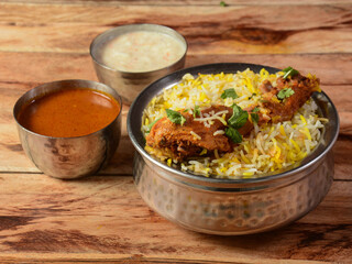 Traditional Hyderabadi Chicken dum Biryani made of Basmati rice cooked with masala spices, served with Onion raita and Salan, selective focus