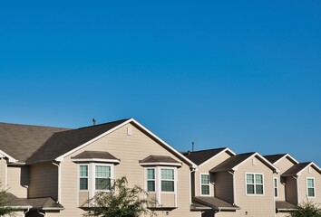 Townhome rooftops in the suburbs joined together tapering off into the distance under a clear blue...
