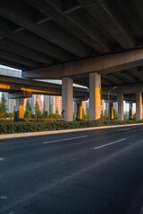 Urban road under overpass bridge at sunset.