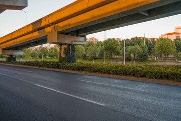 Naklejka premium Urban road under overpass bridge at sunset.