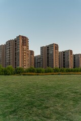 Obraz premium Residential buildings with green grass in front at sunset.