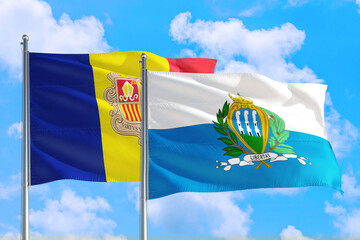 San Marino and Andorra national flag waving in the windy deep blue sky. Diplomacy and international relations concept.