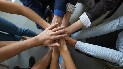 Joining leader. Close up top view of diverse people business partners friends colleagues stacking palms in pile as symbol of racial and gender equality, unity, support of good proposal project startup