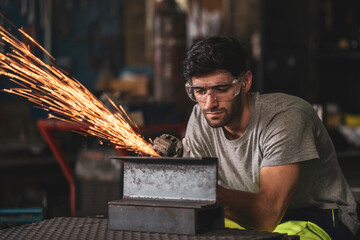 A mechanic wearing safety equipment and operating angle grinder - Metal factory - Industry concept