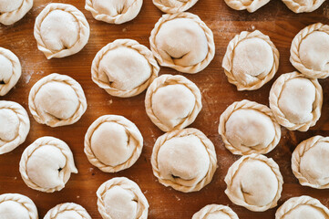pile of small homemade uncooked dumplings with meat on kitchen table. national traditional Russian cuisine. do it yourself. top view, flat lay
