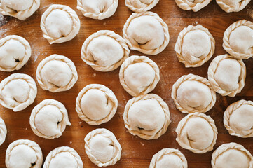 pile of small homemade uncooked dumplings with meat on kitchen table. national traditional Russian cuisine. do it yourself. top view, flat lay