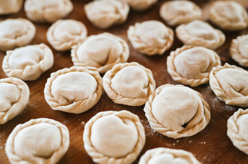 pile of small homemade uncooked dumplings with meat on kitchen table. national traditional Russian cuisine. do it yourself. top view, flat lay