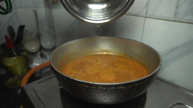 A female hand putting eggs in red curry.