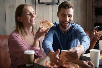 Tastes great. Happy excited young male and female loving couple mates colleagues spending good time at favorite pizzeria with group of friends on weekend having fun enjoying pizza laughing chatting