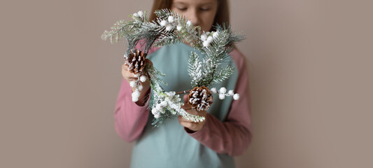 funny girl child in pajamas holding a Christmas wreath, gift box, cozy New Year and Christmas photos, minimalism, pastel delicate colors