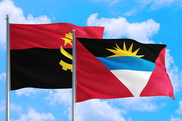 Antigua and Barbuda and Angola national flag waving in the windy deep blue sky. Diplomacy and international relations concept.